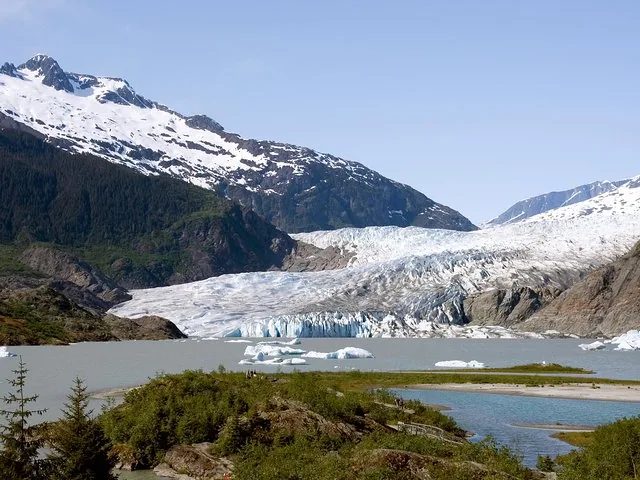 Wide view of Mendenhall Glacier flowing into the lake surrounded by mountains.