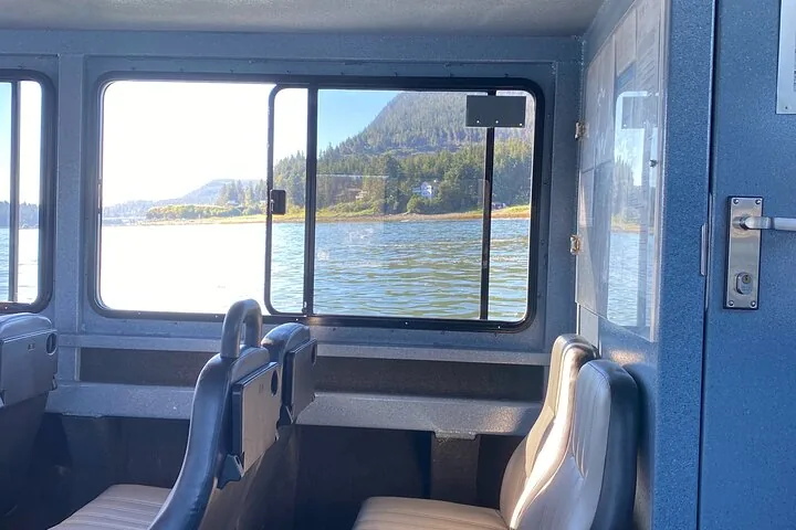 Blick aus dem Inneren eines Bootes aus dem Fenster auf die bewaldete Küstenlinie.