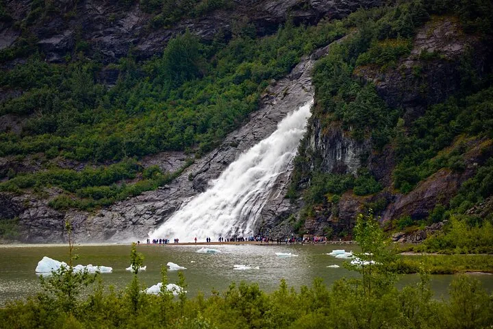 People gathering at the base of Nugget Falls near Mendenhall Glacier lake.