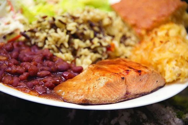 Un plato de salmón a la parrilla, frijoles, arroz y guarniciones en un asado de salmón.